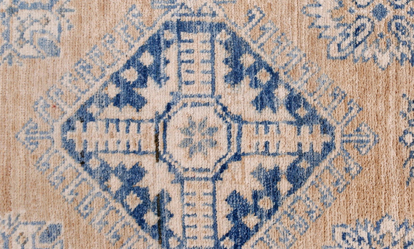 A handmade Afghan Super Kazakh runner featuring a blue geometric diamond pattern on a tan wool base.