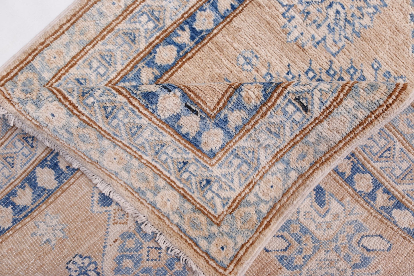 A folded Afghan Super Kazakh runner featuring traditional blue and beige geometric patterns.