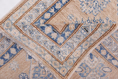 A folded Afghan Super Kazakh runner featuring traditional blue and beige geometric patterns.