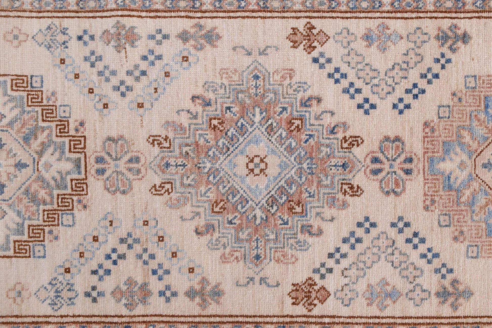 An Afghan Super Kazakh runner featuring traditional geometric motifs in blue and brown on a cream base.