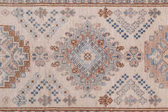 An Afghan Super Kazakh runner featuring traditional geometric motifs in blue and brown on a cream base.