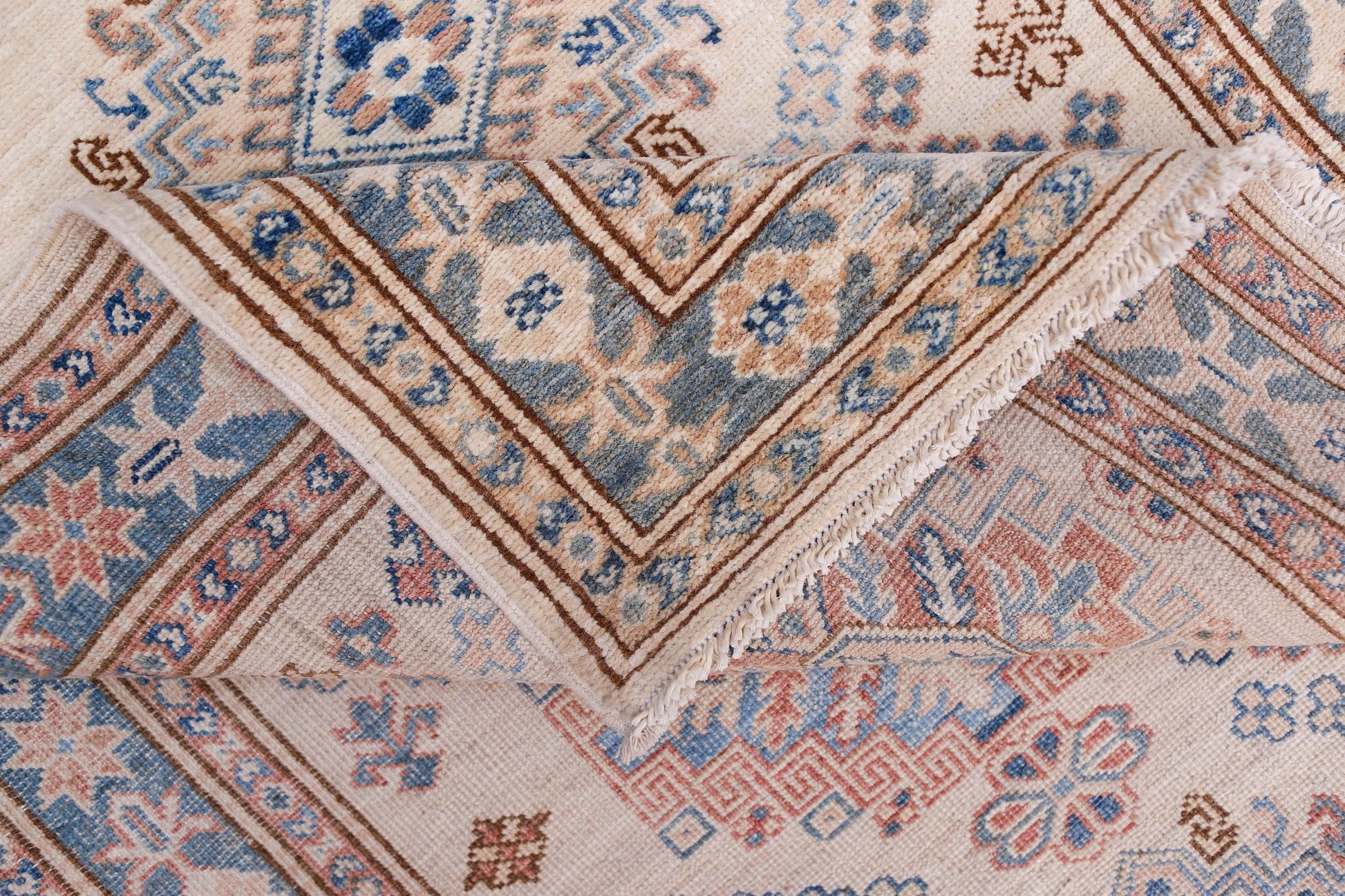 A handmade Afghan Super Kazakh runner featuring traditional geometric motifs in blue, pink, and cream.