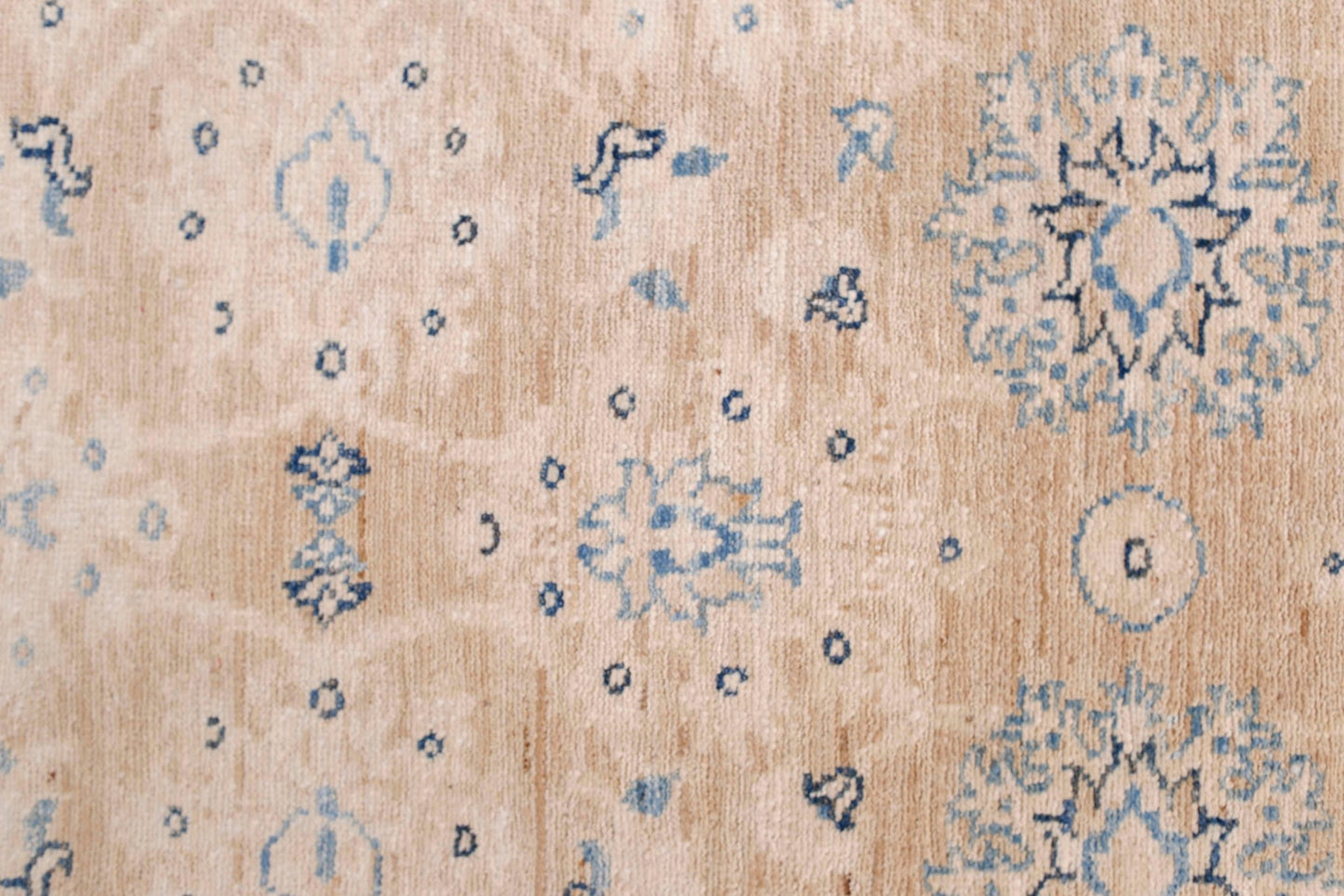 A handmade Afghan Super Kazakh runner featuring traditional blue floral motifs on a beige wool base.
