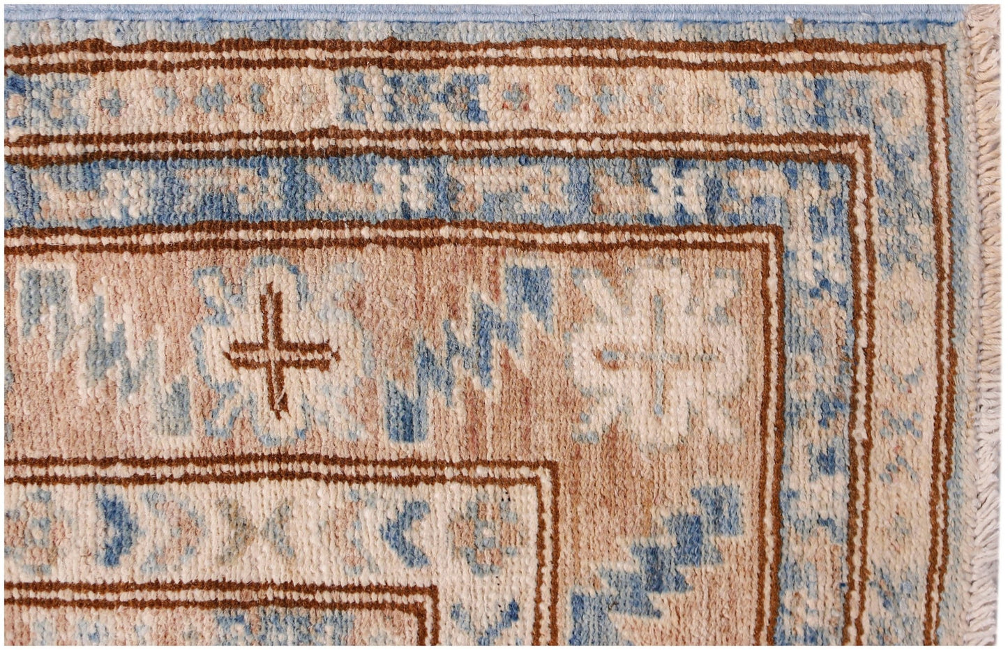 A close-up of an Afghan Super Kazakh runner featuring traditional geometric motifs in blue and tan.