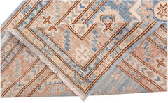 A folded Afghan Super Kazakh runner featuring traditional geometric motifs in blue and tan wool.