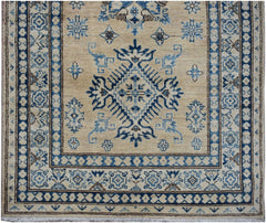 Handmade Afghan Super Kazakh runner rug featuring a blue geometric medallion on a beige field.