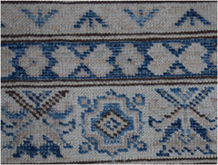 A close-up of an Afghan Super Kazakh runner featuring traditional blue and beige geometric motifs.