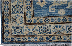 A handmade Afghan Super Kazakh runner featuring a geometric blue and beige pattern with fringe.