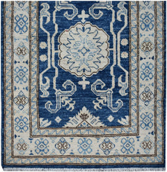 An Afghan Super Kazakh runner rug featuring a central floral medallion on a deep blue field.