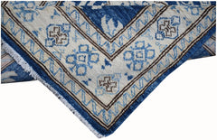 A corner view of a handmade Afghan Super Kazakh runner featuring blue and brown geometric patterns.
