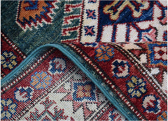 A folded Afghan Super Kazakh runner featuring traditional geometric motifs in red, blue, and cream.