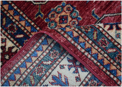 A close-up of a handmade Afghan Super Kazakh runner featuring traditional geometric motifs in red, blue, and cream wool.