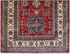 An Afghan Super Kazakh runner featuring a red field with a central blue geometric medallion.