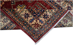 A folded Afghan Super Kazakh runner featuring traditional geometric motifs in red, blue, and cream.