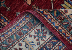 A corner of a handmade Afghan Super Kazakh runner featuring traditional red, blue, and cream motifs.