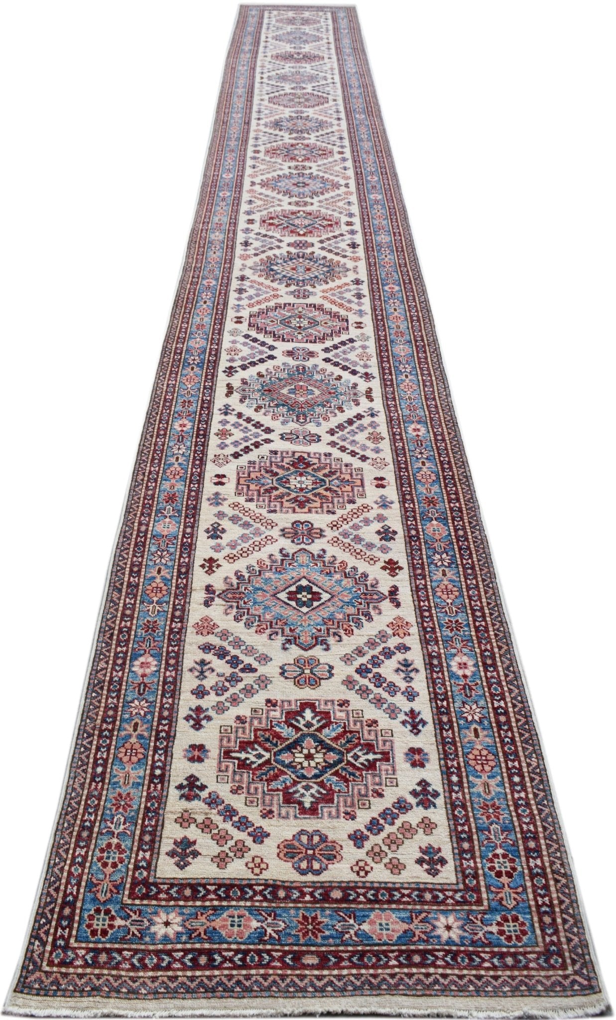 A long, handmade Afghan Super Kazakh runner rug featuring traditional geometric motifs in red, blue, and cream.