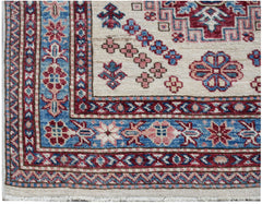 A handmade Afghan Super Kazakh runner featuring traditional geometric motifs in red and blue.