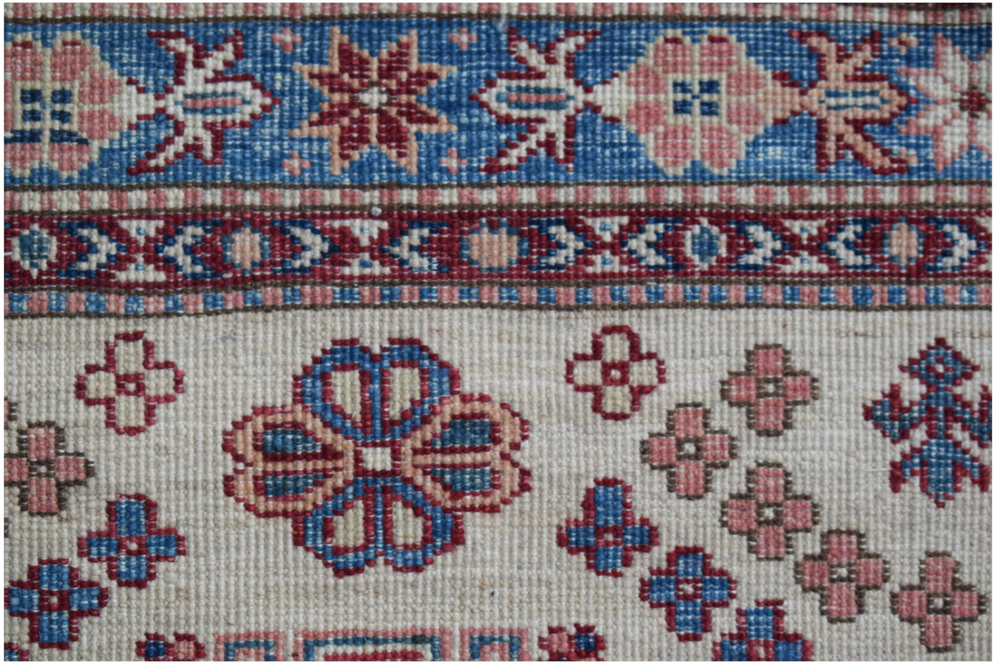 Handmade Afghan Super Kazakh runner featuring traditional floral motifs in blue and pink wool.