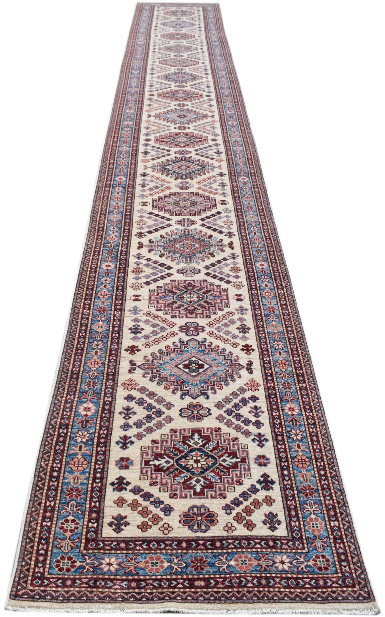 A long, handmade Afghan Super Kazakh runner rug featuring traditional geometric patterns in red and blue.