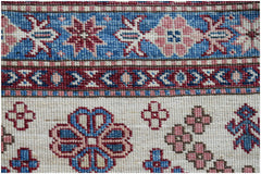 A close-up of an Afghan Super Kazakh runner featuring traditional floral motifs in blue and pink.