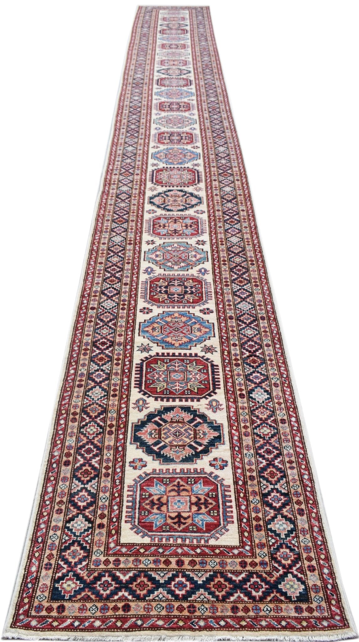 A long, handmade Afghan Super Kazakh runner rug featuring traditional geometric motifs in red, blue, and cream.