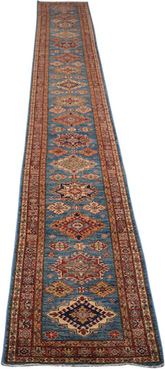 A long, handmade Afghan Super Kazakh runner rug featuring traditional geometric patterns in blue.