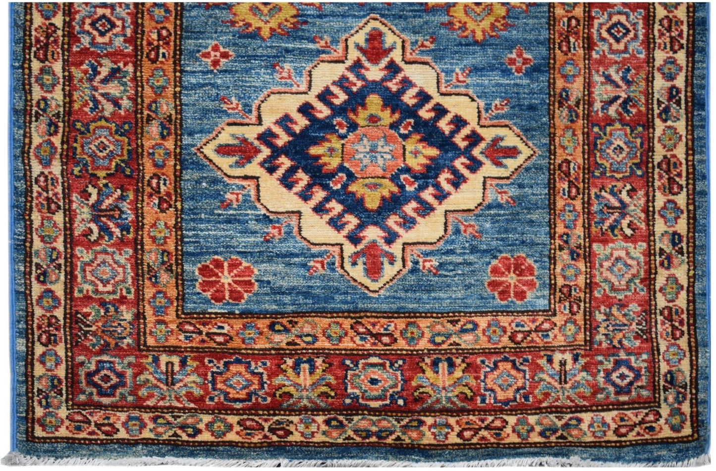 An Afghan Super Kazakh runner rug featuring a central geometric medallion on a blue field.