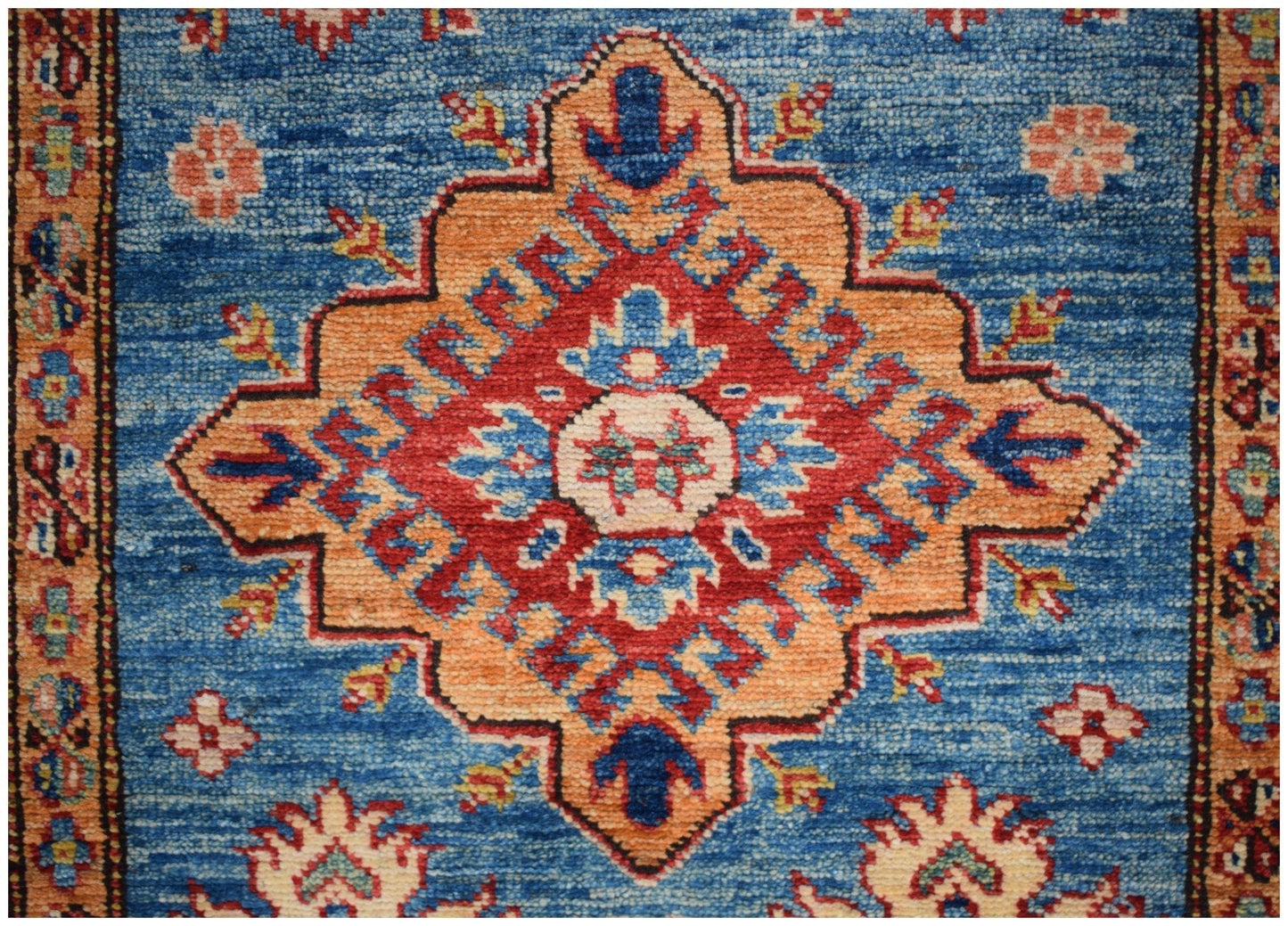 Handmade Afghan runner rug featuring a central geometric medallion in red, orange, and blue.