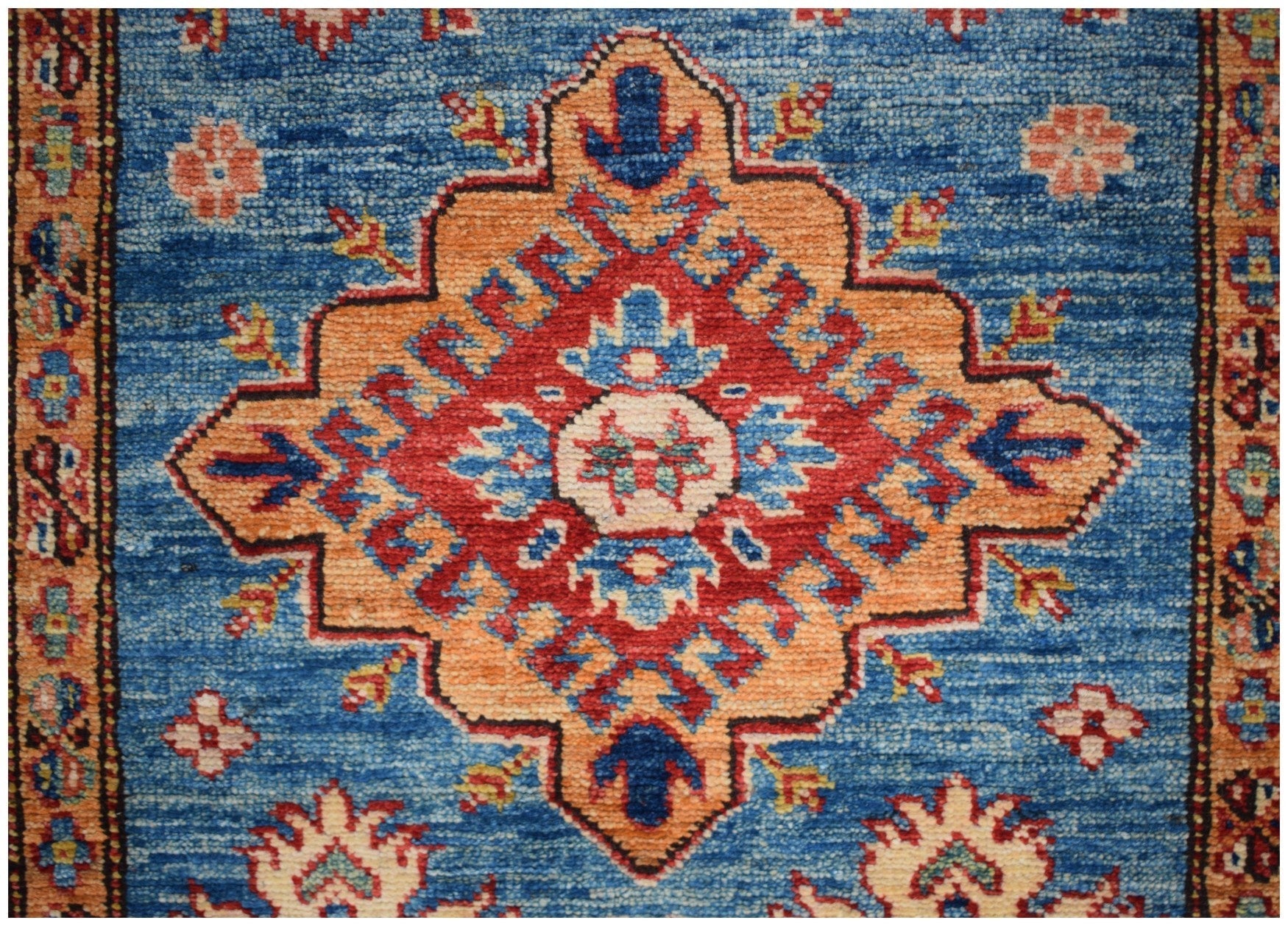Handmade Afghan runner rug featuring a central geometric medallion in red, orange, and blue.