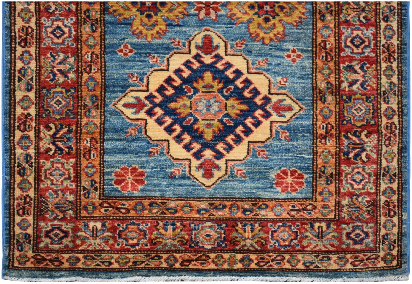 Handmade Afghan Super Kazakh runner rug featuring a central geometric medallion on a blue field.