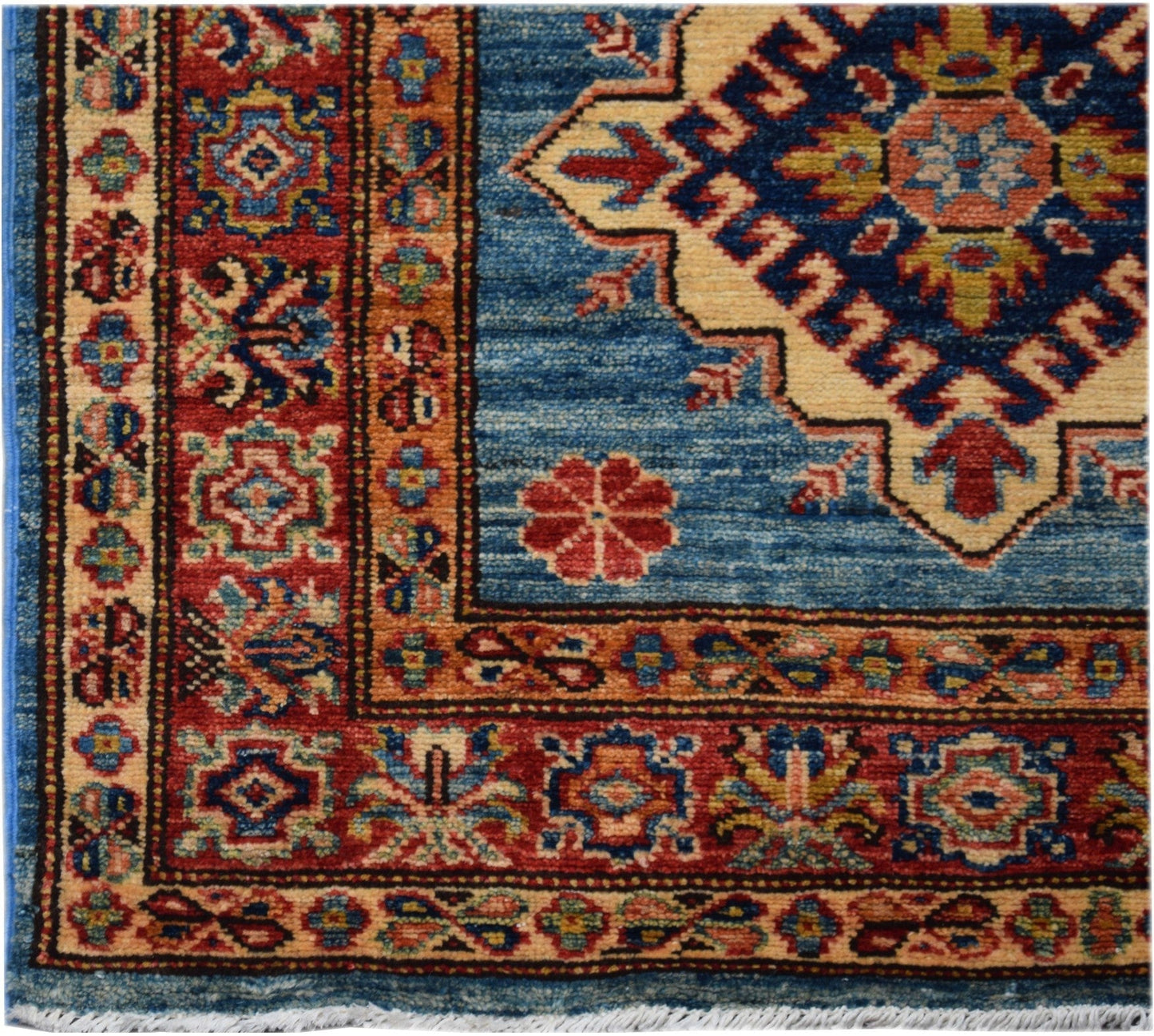 A handmade Afghan Super Kazakh runner rug featuring a blue field with geometric floral motifs.