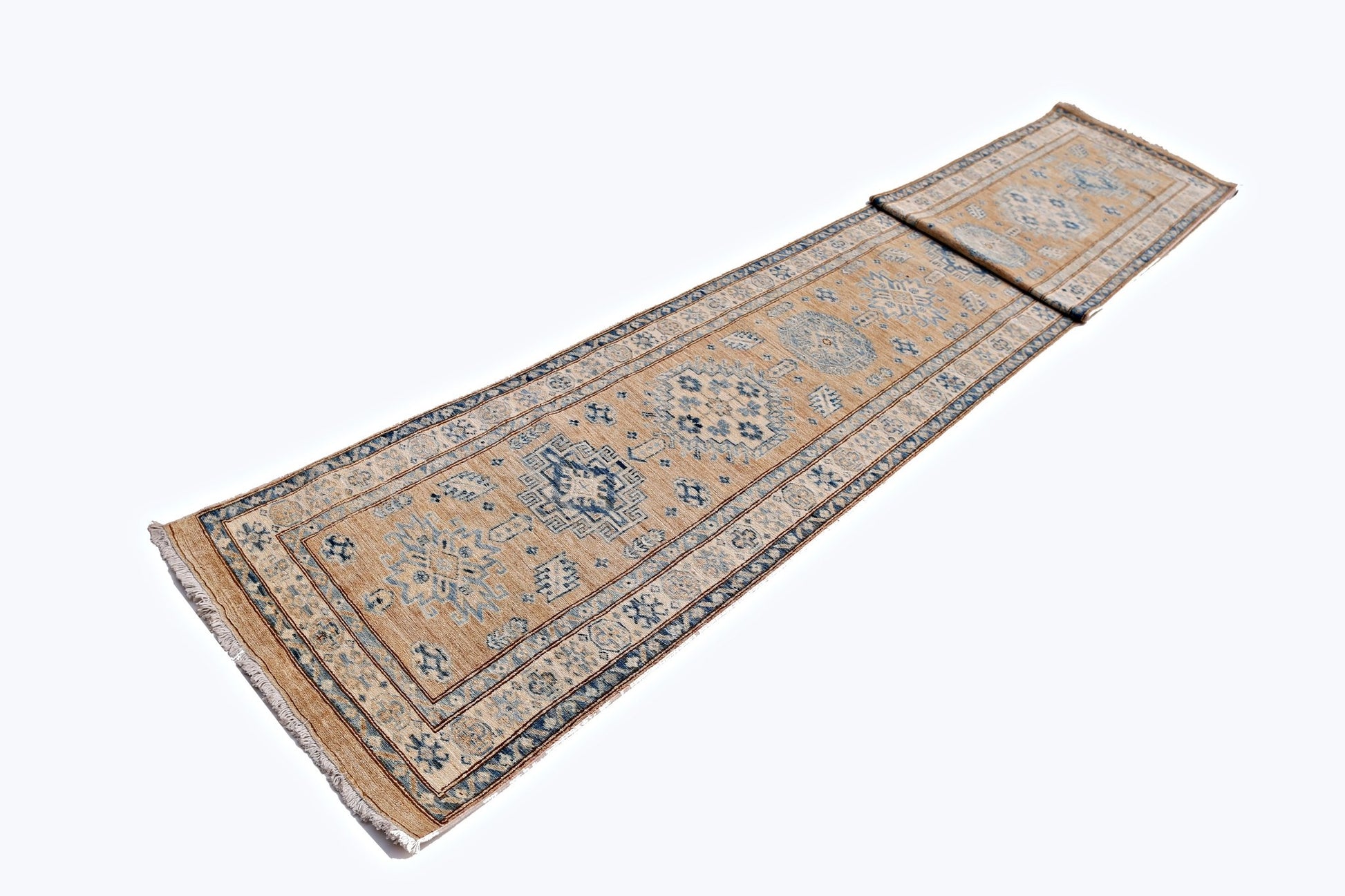 A long, handmade Afghan Super Kazakh runner rug featuring traditional blue motifs on a tan field.