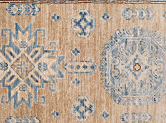 A handmade Afghan Super Kazakh runner featuring traditional blue geometric motifs on a tan wool base.
