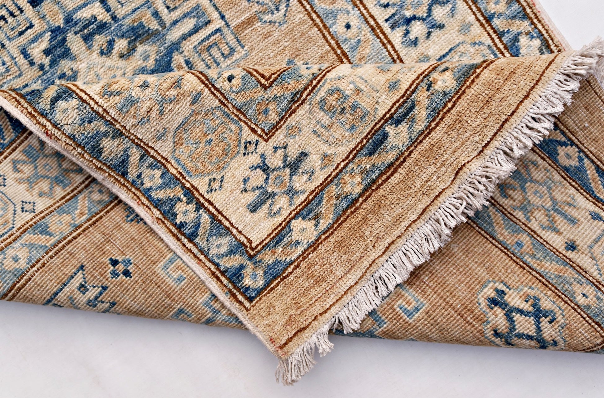A handmade Afghan Super Kazakh runner featuring traditional blue motifs on a tan wool background.