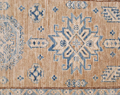 A handmade Afghan Super Kazakh runner featuring traditional blue geometric motifs on a tan wool base.