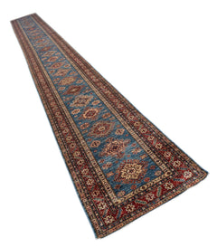 A long, handmade Afghan Super Kazakh runner rug featuring traditional geometric motifs in blue and red.