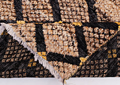 An Afghan Yekta rug featuring a black and tan geometric pattern with a textured pile and fringe.