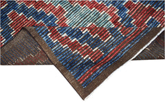 A hand-knotted Afghan rug featuring a geometric pattern in red, blue, and white wool.