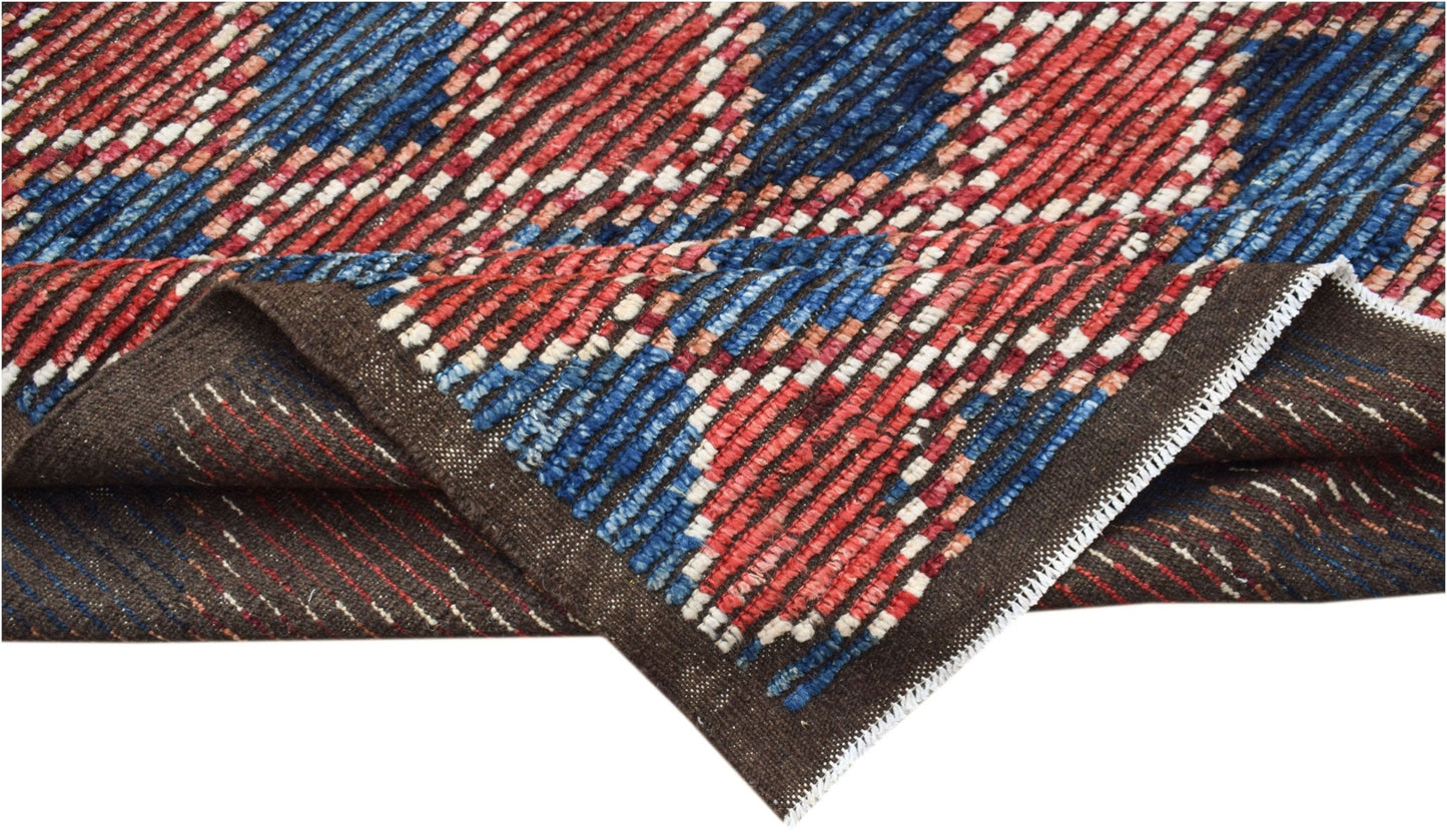 A hand-knotted Afghan rug featuring a geometric pattern in red, blue, and white on a brown base.