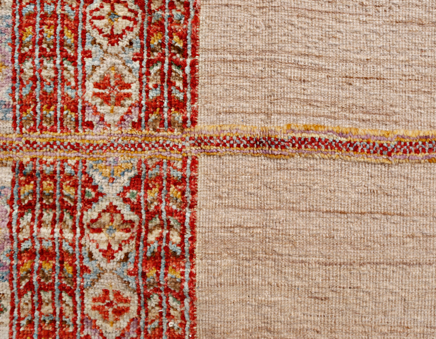 An Afghan Yekta rug featuring a textured beige field contrasted by a vibrant red patterned border.