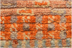 A close-up of an Afghan Yekta rug featuring a textured, hand-knotted pattern in shades of orange.