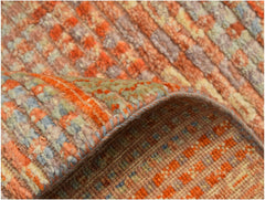 A close-up of a handmade Afghan Yekta rug featuring a textured orange and grey wool pile.