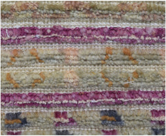 A close-up of a handmade Afghan rug featuring horizontal stripes of textured wool in purple and tan.