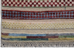 A handmade Afghan Yekta runner featuring horizontal bands of geometric patterns and colorful wool.