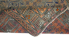 An antique Afghan Balouch rug with a folded corner revealing its intricate geometric wool pattern.