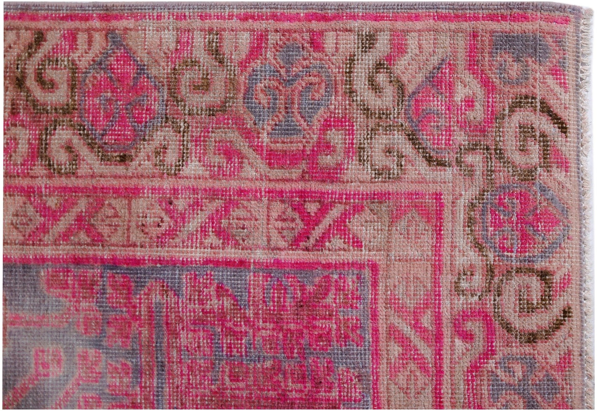 An antique handwoven Khotan rug featuring an intricate pomegranate pattern in vibrant pink tones.
