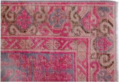 An antique handwoven Khotan rug featuring an intricate pomegranate pattern in vibrant pink tones.