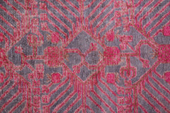 An antique handwoven Khotan rug featuring an intricate pomegranate pattern in vibrant pink.