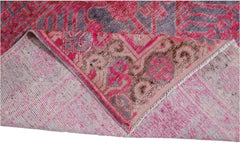 An antique handwoven Khotan rug featuring an intricate pomegranate pattern in vibrant pink tones.