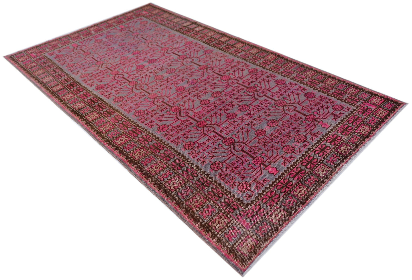 An antique handwoven Khotan rug featuring a vibrant pink pomegranate pattern on a grey background.